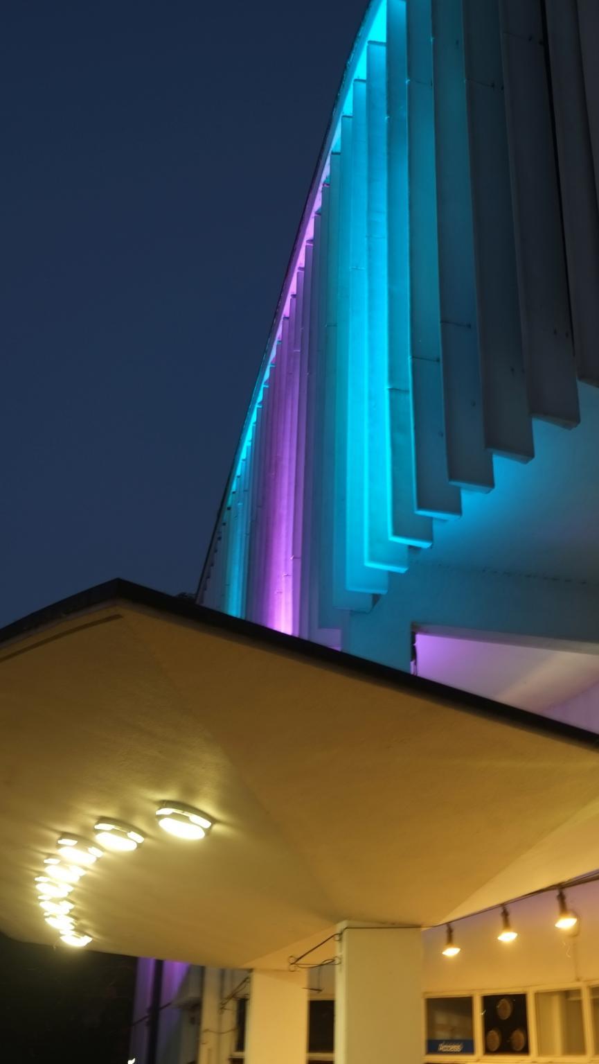 The external of the theatre lit by pink and blue lights